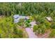 Aerial view of a secluded home nestled in a lush forest with mature trees, a detached garage, and circular driveway at 6565 Marshmerry Ln, Evergreen, CO 80439