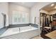 Luxurious soaking tub with modern fixtures, mosaic tile surround, and plantation shutters at 6565 Marshmerry Ln, Evergreen, CO 80439