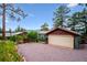 Detached two-car garage with gravel driveway, wood gate, and mature landscaping at 6565 Marshmerry Ln, Evergreen, CO 80439