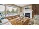 Sun-filled living room with fireplace and windows framing the mountain view and outdoor deck at 6565 Marshmerry Ln, Evergreen, CO 80439