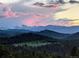 Breathtaking mountain view with a colorful pink sunset sky over lush green hills at 6565 Marshmerry Ln, Evergreen, CO 80439