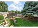 Private backyard with mature trees, garden beds, and a cozy seating area at 470 S Queen St, Lakewood, CO 80226