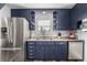 Cozy kitchen with navy cabinets, stainless steel appliances, and a double basin sink underneath a window at 7296 Quivas St, Denver, CO 80221