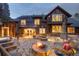 A spacious stone patio with a fire pit, lounge chairs, and hot tub surrounded by a wooded yard at 215 Royal Tiger Rd, Breckenridge, CO 80424