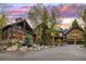 A luxurious stone and wood home with a circular driveway is framed by a vibrant sunset sky at 215 Royal Tiger Rd, Breckenridge, CO 80424