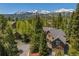 Stunning aerial view of a luxury home surrounded by lush greenery with snow-capped mountains in the background at 215 Royal Tiger Rd, Breckenridge, CO 80424