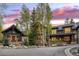 A luxurious stone and wood home with a circular driveway is framed by a vibrant sunset sky at 215 Royal Tiger Rd, Breckenridge, CO 80424