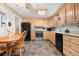 Traditional kitchen featuring wood cabinets, black appliances, and a cozy dining area at 6919 S Valentia St, Centennial, CO 80112