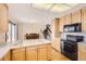 Open-concept kitchen with wood cabinets, black appliances, and a view into the adjacent living space at 10020 Bryant St, Denver, CO 80260