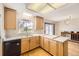 Well-lit kitchen with light wood cabinets, black dishwasher, and a view of the outdoor scenery at 10020 Bryant St, Denver, CO 80260