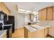 Functional kitchen with light wood cabinets, black appliances, and ample counter space at 10020 Bryant St, Denver, CO 80260