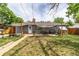 Spacious backyard with patio area, a greenhouse, fire pit, and a well-maintained lawn at 2612 Meadowbrook Dr, Denver, CO 80221