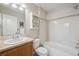 Bathroom with wood cabinets, framed mirror, and combination tub and shower at 2230 Valentia St, Denver, CO 80238
