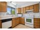 Kitchen features wood cabinets, white appliances, a double sink and a view of the trees outside at 6411 W 82Nd Dr, Arvada, CO 80003