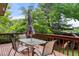 Outdoor wooden deck with a table, chairs, umbrella and surrounding trees at 8571 W 71St Cir, Arvada, CO 80004