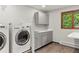 Laundry room featuring modern washer/dryer, cabinets, countertop, and wood flooring at 8571 W 71St Cir, Arvada, CO 80004