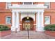 Elegant entrance to building with ornate wood doors, white columns, and 