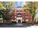 Three-story red brick condo building with mature trees, white trim, and inviting entrance at 836 E 17Th Ave # 2B, Denver, CO 80218