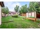 Spacious backyard with a well-kept lawn, garden, shed, and mature trees at 1470 S Yates St, Denver, CO 80219