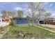 Charming single-story home with blue siding, red door, and driveway with carport surrounded by lush greenery at 41 Cortez St, Denver, CO 80221