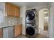 Well-lit kitchen showcasing stainless steel dishwasher, wood cabinets, and stacked washer/dryer near doorway at 41 Cortez St, Denver, CO 80221