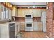 Traditional kitchen with brick accents, white appliances, and wood-look floors at 16308 E Wyoming Dr, Aurora, CO 80017