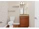 A charming half-bathroom offers a decorative mirror, wood floors, and designer wallpaper at 1208 S Valentia Ct, Denver, CO 80247