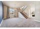 Open-concept living room with plush carpeting, staircase, large windows and a modern chandelier lighting fixture at 1208 S Valentia Ct, Denver, CO 80247