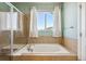 Bathroom featuring a large tub, glass-enclosed shower, and tiled walls at 1208 S Valentia Ct, Denver, CO 80247