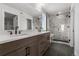 Modern bathroom featuring double sinks, a vanity, a large mirror, and a marble tiled shower at 14281 Currant, Broomfield, CO 80020