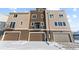 Modern townhome featuring multi-tone siding, attached garages, and front balconies, set against a snowy landscape at 14281 Currant, Broomfield, CO 80020