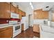 Kitchen with wood cabinets, white appliances and hardwood floor at 11565 Decatur St # 7D, Denver, CO 80234