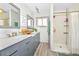 Bathroom featuring gray vanity with dual sinks and walk-in shower at 1673 Woodmoor Dr, Monument, CO 80132