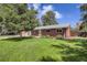 Landscaped front yard of brick home with green lawn and mature trees casting dappled shadows on a sunny day at 3205 Moorhead Ave, Boulder, CO 80305