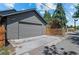 A view of the detached two-car garage with a gray door and siding with the driveway and street at 3770 Osceola St, Denver, CO 80212
