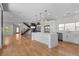 Open-concept living space with modern chandelier and hardwood floors leads into kitchen with stainless appliances at 3770 Osceola St, Denver, CO 80212