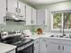 A kitchen featuring stainless appliances, white cabinets, and a window with a wooded view at 11650 Baca Rd, Conifer, CO 80433