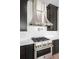 Modern kitchen featuring a stainless steel range hood, range, marble counters, and dark wood cabinets at 11115 Evening Hunt Rd, Franktown, CO 80116