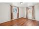 Bedroom featuring hardwood floors and two bright windows dressed with neutral-toned curtains at 10 Merideth Ln, Longmont, CO 80501