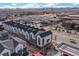 Aerial view of modern townhouses, nearby mountains, and a gas station in a bustling area at 5188 Ward Rd, Wheat Ridge, CO 80033