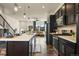 Open-concept kitchen features dark cabinets, stainless steel appliances, and a large island flowing into the living area at 5188 Ward Rd, Wheat Ridge, CO 80033