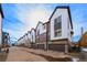 A row of modern townhouses with attached garages on a concrete street under a bright blue sky at 5188 Ward Rd, Wheat Ridge, CO 80033