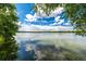 Scenic lake view with water reflecting a blue sky with puffy white clouds, framed by lush greenery on the shoreline at 4200 W 17Th Ave # 212, Denver, CO 80204