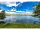 Scenic lake view with grassy shore, clear blue sky, and a bird perched on a branch in the foreground at 4200 W 17Th Ave # 212, Denver, CO 80204