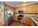 Modern kitchen with stainless steel appliances, warm wood cabinetry, and granite countertops at 7453 E 26Th Ave # 2, Denver, CO 80238