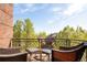 Relaxing balcony with wicker chairs, glass-top tables, and a view of mature trees and neighborhood at 907 E 22Nd Ave, Denver, CO 80205