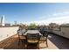 Rooftop patio furnished with a large dining table and chairs set against a city backdrop at 907 E 22Nd Ave, Denver, CO 80205