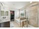 Bright bathroom featuring a double vanity, soaking tub, walk-in shower and barn-door leading to walk-in closet at 24356 E Powers Ave, Aurora, CO 80016
