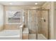 Bathroom featuring tiled walk-in shower with glass door, soaking tub under a window at 24356 E Powers Ave, Aurora, CO 80016