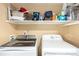 Well-organized laundry area with modern front load washer, dryer, and ample shelving for storage at 5972 S Zante Way, Aurora, CO 80015